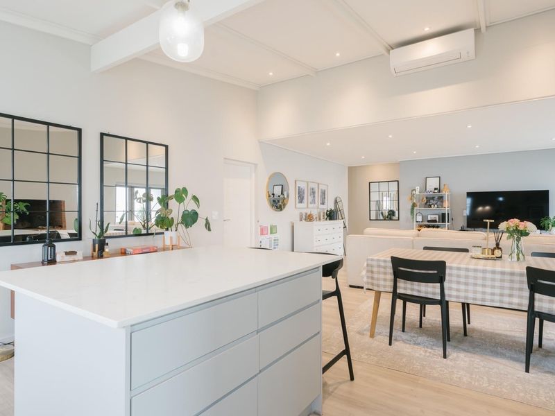 Bright open-plan living area featuring a modern kitchen island, recessed lighting, and split-system air conditioning, seamlessly connecting to the dining and lounge space.