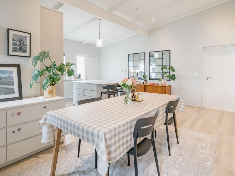 Bright open-plan living and dining area featuring light laminate flooring, recessed ceiling lighting, and a modern kitchen island.