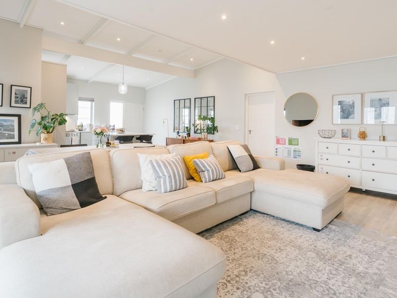 A bright and spacious open-plan living area featuring modern laminate flooring, recessed downlighting, and a coffered ceiling, seamlessly connecting to the kitchen.