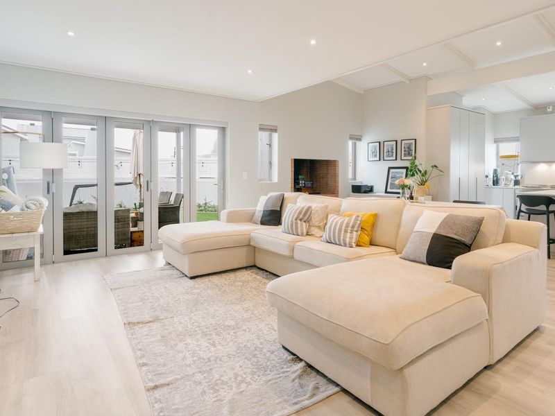 Spacious open-plan living area featuring a modern kitchen with island, built-in fireplace, and seamless access to the patio through large bi-fold doors.