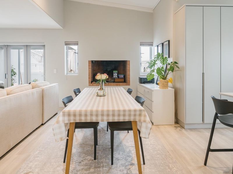 Spacious open-plan living and dining area featuring a built-in fireplace, modern laminate flooring, and integrated cabinetry with a breakfast bar.