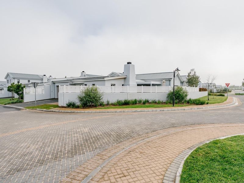 A street-level view of the property exterior, showcasing the paved driveway, boundary wall, and modern architectural features of the house.