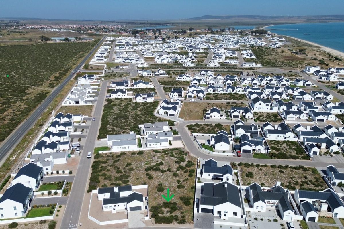 Aerial view of a vacant residential plot situated within a developed coastal estate, featuring established road infrastructure and surrounding residential properties.