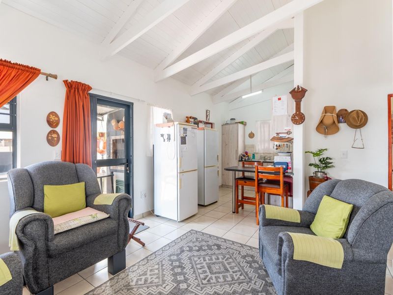 Open-plan living area featuring exposed timber ceiling beams, tiled flooring, and direct access to an outdoor patio area.