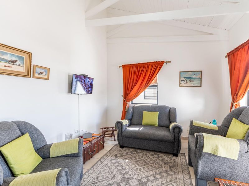 A bright living room featuring a high vaulted ceiling with exposed timber beams and neutral tiled flooring.