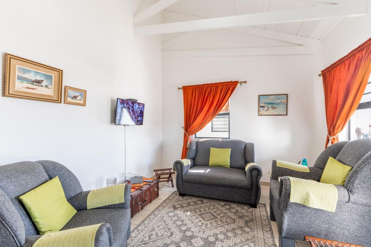 A bright living room featuring a high vaulted ceiling with exposed timber beams and neutral tiled flooring.