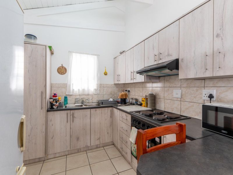 Functional kitchen featuring light wood-look cabinetry, dark countertops, tiled backsplash, and a vaulted ceiling, providing a practical workspace with essential built-in appliances.
