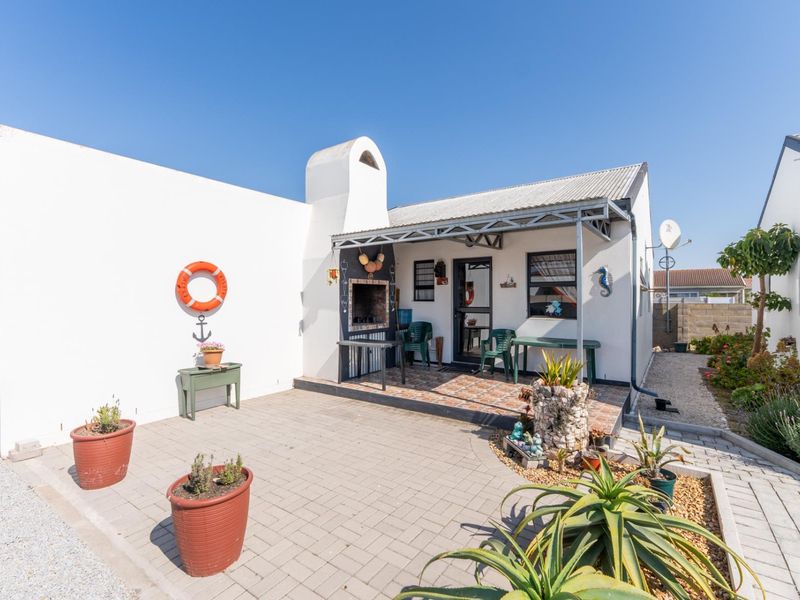 A well-maintained outdoor patio area featuring a built-in braai, tiled flooring, and a covered veranda, perfect for outdoor entertaining.