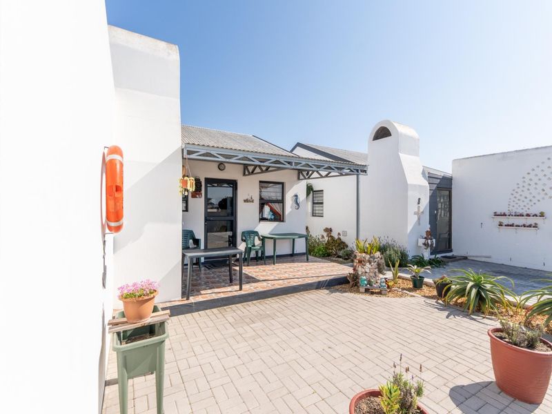 A well-maintained paved courtyard featuring a covered patio area and a built-in outdoor fireplace, ideal for relaxed outdoor living.