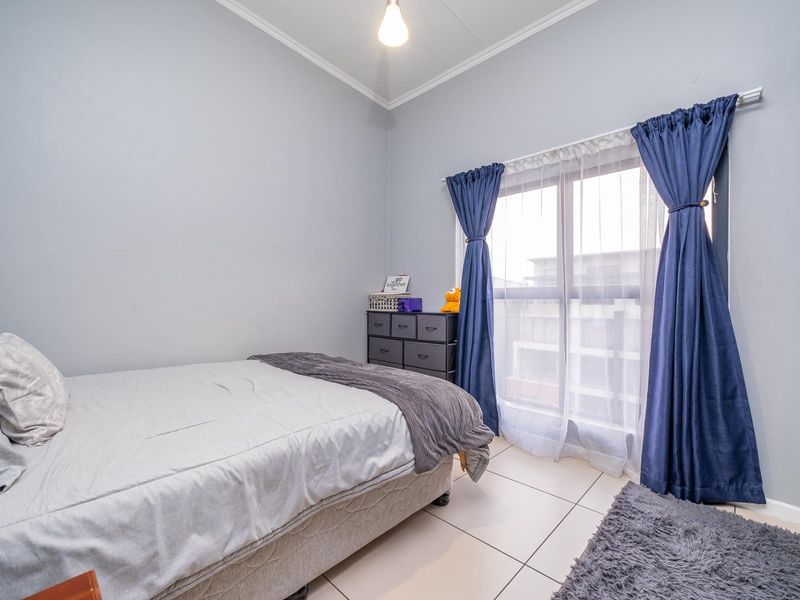 A well-lit bedroom featuring tiled flooring, a built-in wardrobe, and a sliding glass door providing natural light.