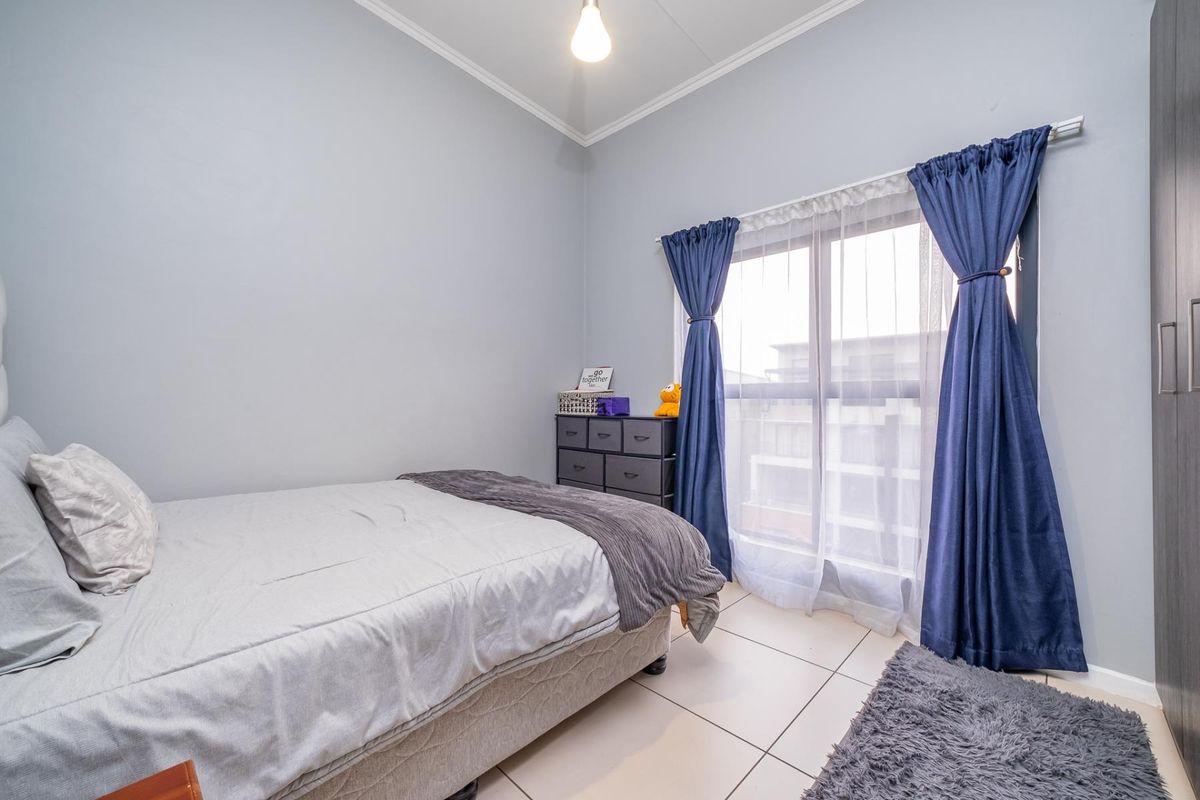 A well-lit bedroom featuring tiled flooring, a built-in wardrobe, and a sliding glass door providing natural light.