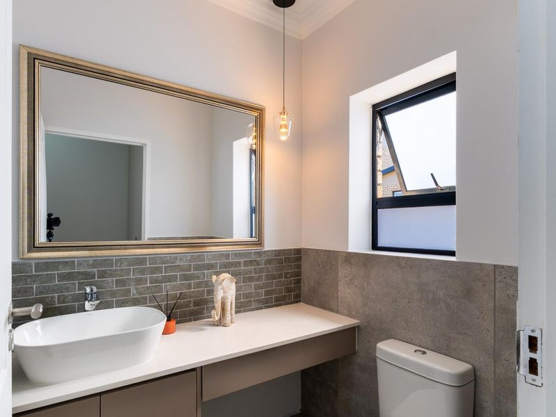Modern bathroom featuring a sleek vessel sink, stone vanity countertop, subway tile backsplash, and a large framed mirror with contemporary pendant lighting.