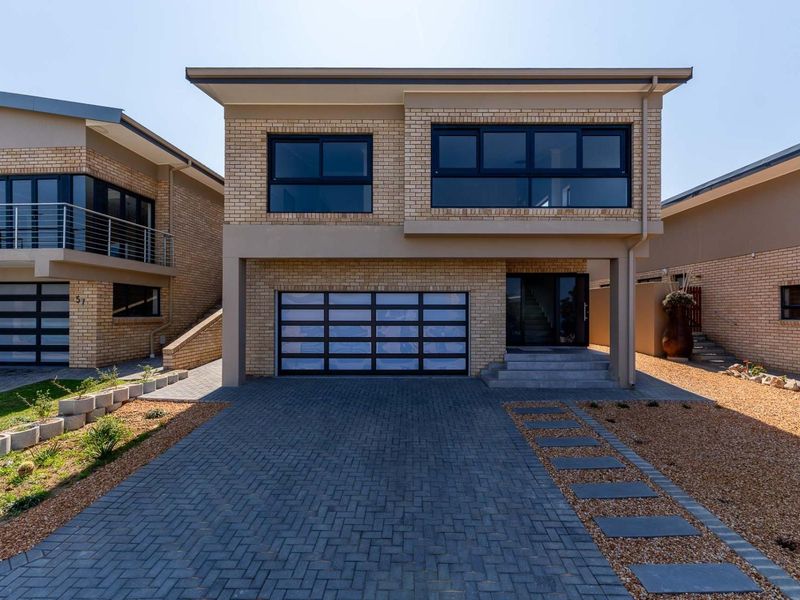 Modern double-storey brick residence featuring a paved driveway, integrated double garage, and contemporary aluminium-framed windows.