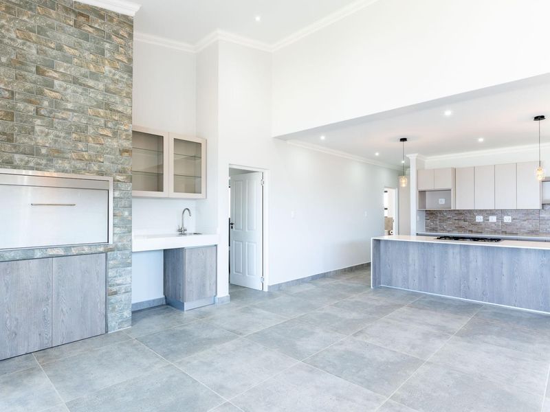 Spacious open-plan living area featuring a modern kitchen with island, gas hob, and a built-in indoor braai with stone feature wall.