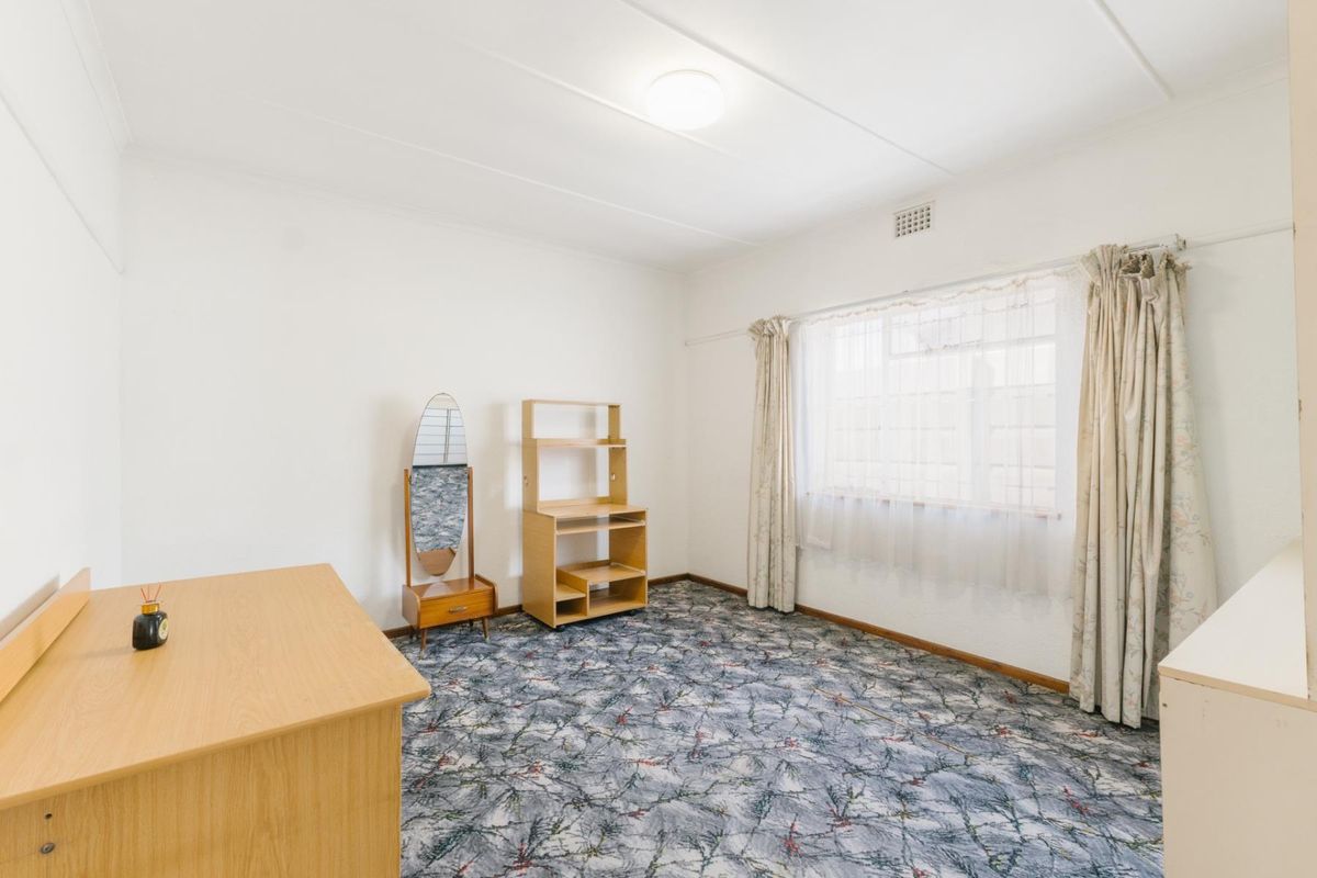 A bedroom featuring patterned carpet flooring and a ceiling vent, offering a blank canvas for potential updates and modernization.