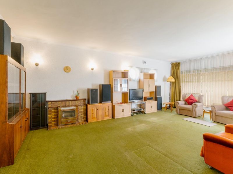 Spacious living room featuring a brick fireplace with a built-in stove, wall sconce lighting, and large windows with floor-to-ceiling curtains.