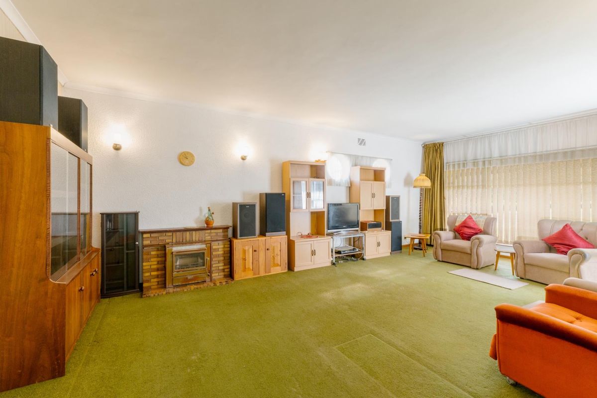 Spacious living room featuring a brick fireplace with a built-in stove, wall sconce lighting, and large windows with floor-to-ceiling curtains.