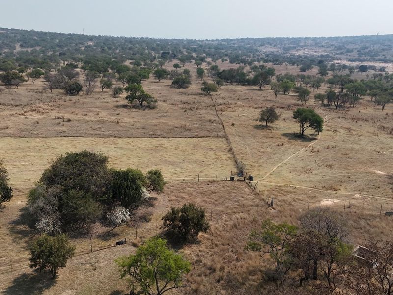An aerial view of expansive farm land featuring natural vegetation, open grazing fields, and established wire fencing boundaries.