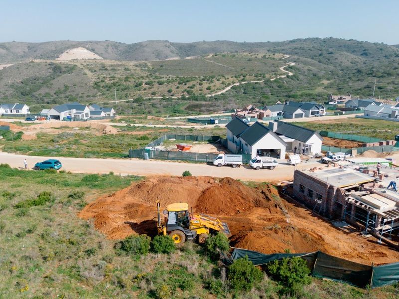 Aerial view of a residential development site showing ongoing construction, excavation work, and surrounding landscape in a developing estate.