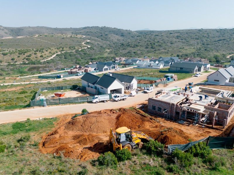 Aerial view of a residential development site showing ongoing construction, earthworks, and surrounding landscape in a developing estate.