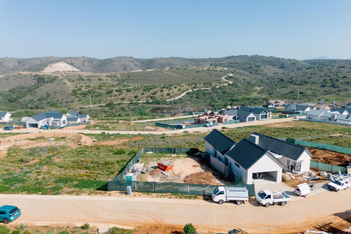 Aerial view of a residential development site featuring newly constructed homes with pitched roofs and surrounding natural landscape.