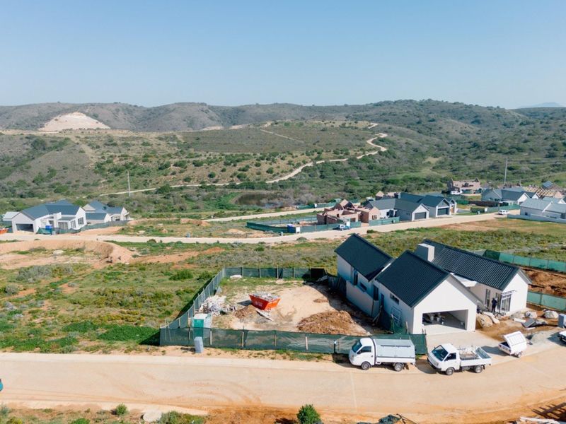 Aerial view of a residential development site featuring newly constructed homes with pitched roofs and surrounding natural landscape.