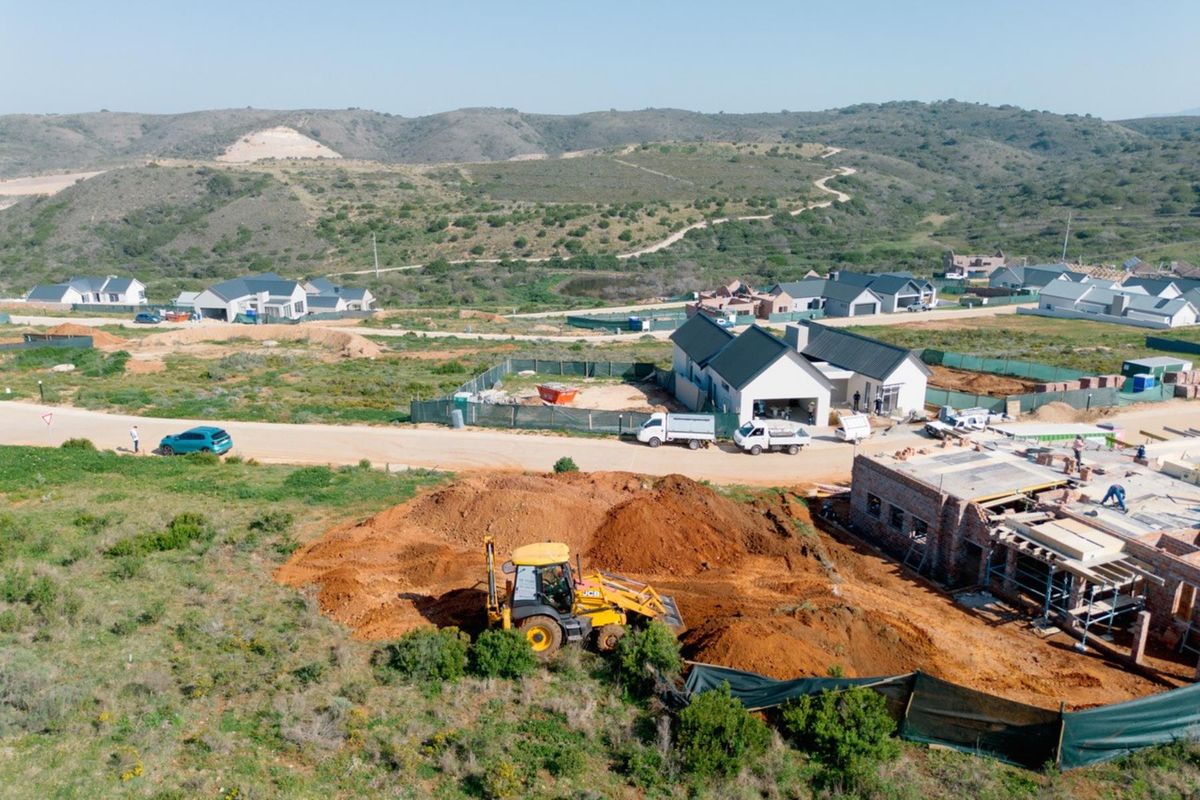 Aerial view of a residential development site showing ongoing construction, excavation work, and surrounding landscape in a developing estate.