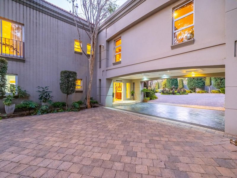 A well-maintained front exterior featuring a paved driveway, a covered porte-cochere entrance, and a balcony with wrought iron detailing.