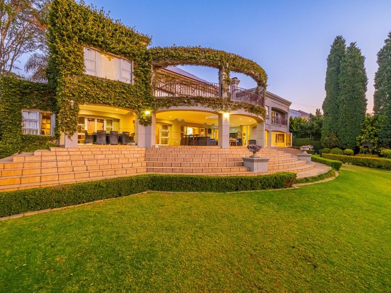 Spacious rear exterior featuring a large covered patio, expansive stone staircase, and a beautifully landscaped garden with mature climbing ivy.