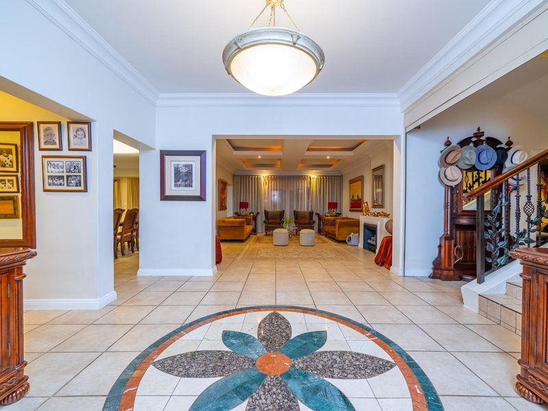 Spacious entrance hall featuring decorative stone floor inlay, elegant crown molding, and a view through to the open-plan living area.