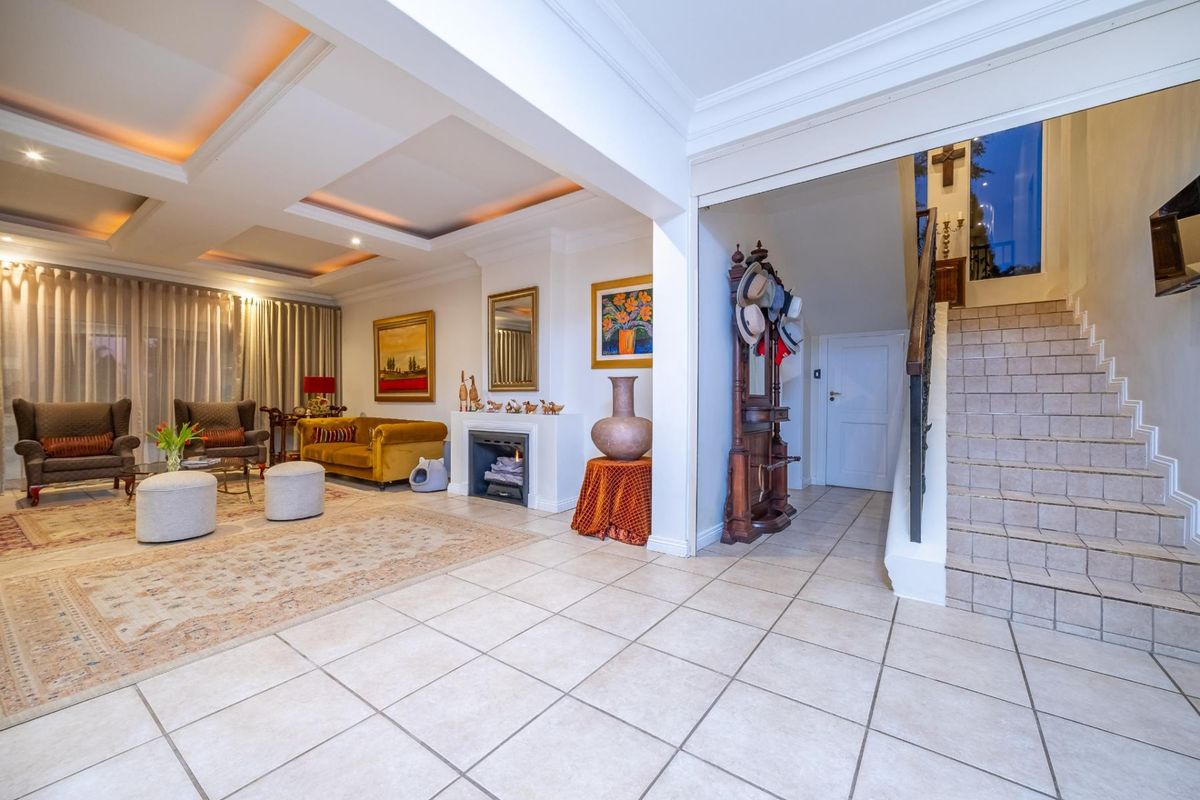 Spacious living area featuring a fireplace, recessed ceiling with cove lighting, and tiled flooring, seamlessly connected to the entrance hall and staircase.