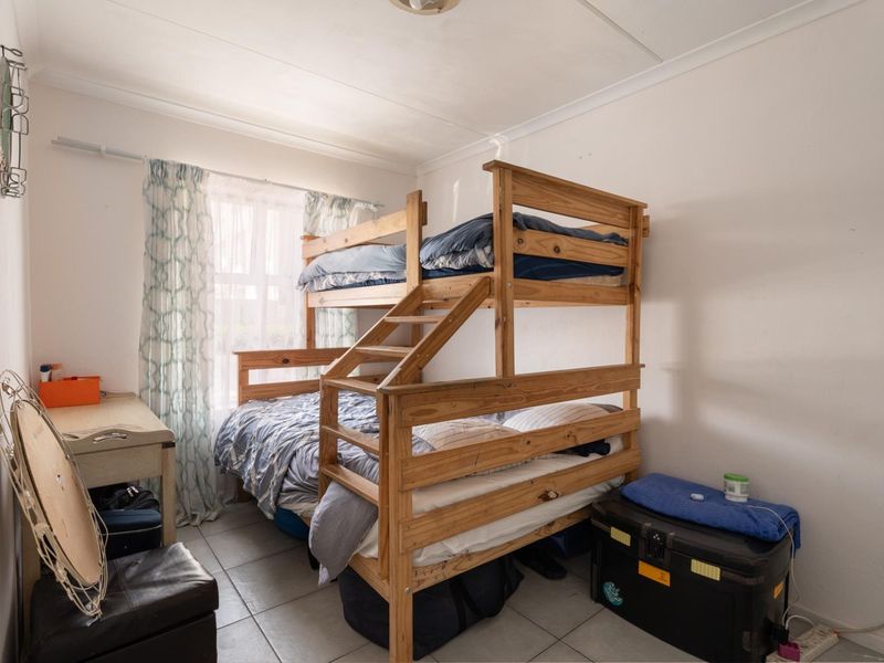 A compact bedroom featuring tiled flooring and coved ceilings, currently utilized with bunk bed sleeping arrangements.