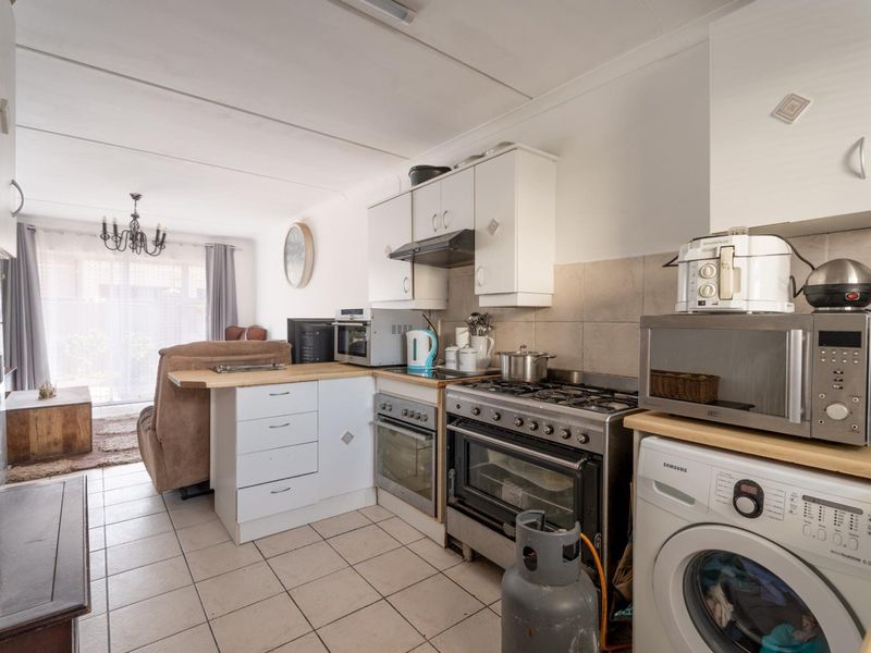 Open-plan kitchen and living area featuring tiled flooring, built-in cabinetry, and a gas stove, offering a functional layout for daily living.