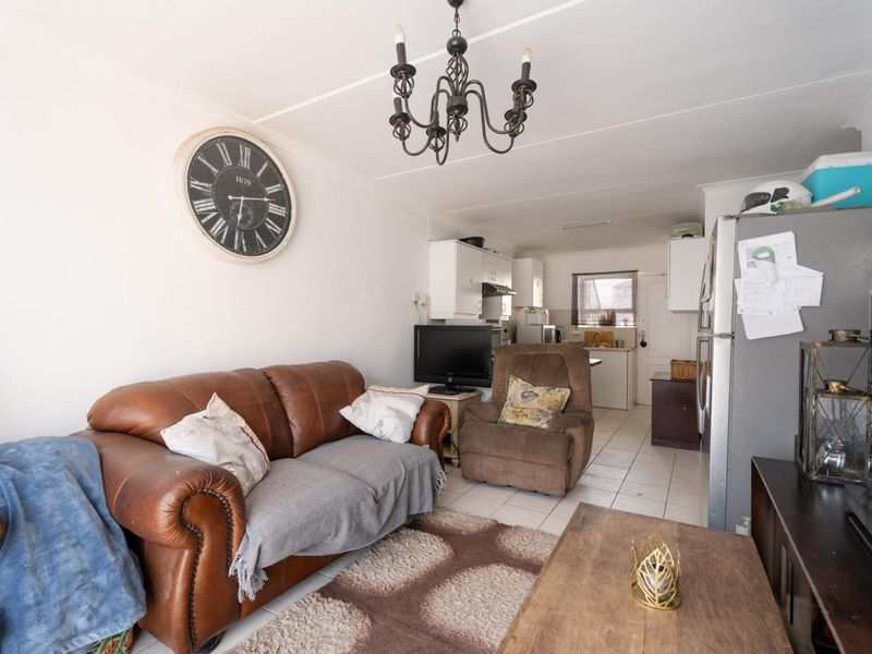 Open-plan living area featuring tiled flooring and an adjoining kitchen space with built-in cabinetry.