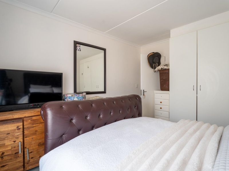 A functional bedroom featuring a built-in wardrobe and coved ceiling, providing essential storage and a neutral foundation for personal styling.