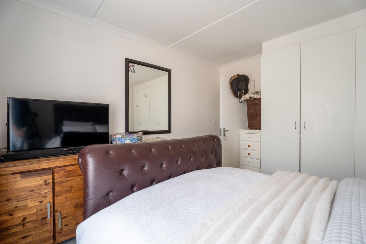 A functional bedroom featuring a built-in wardrobe and coved ceiling, providing essential storage and a neutral foundation for personal styling.