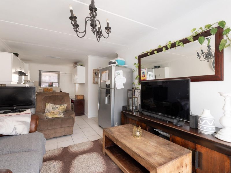 Open-plan living area featuring tiled flooring and an integrated kitchen space with cabinetry and an extractor fan.