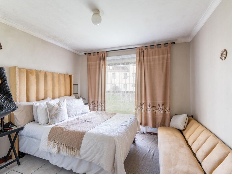 A bedroom featuring tiled flooring and ceiling cornice, requiring cosmetic updates to improve the overall condition of the finishes.