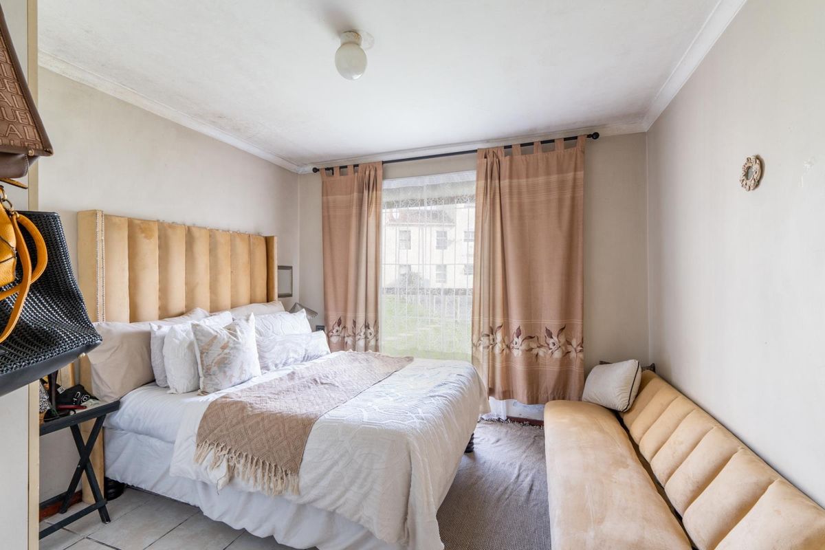 A bedroom featuring tiled flooring and ceiling cornice, requiring cosmetic updates to improve the overall condition of the finishes.