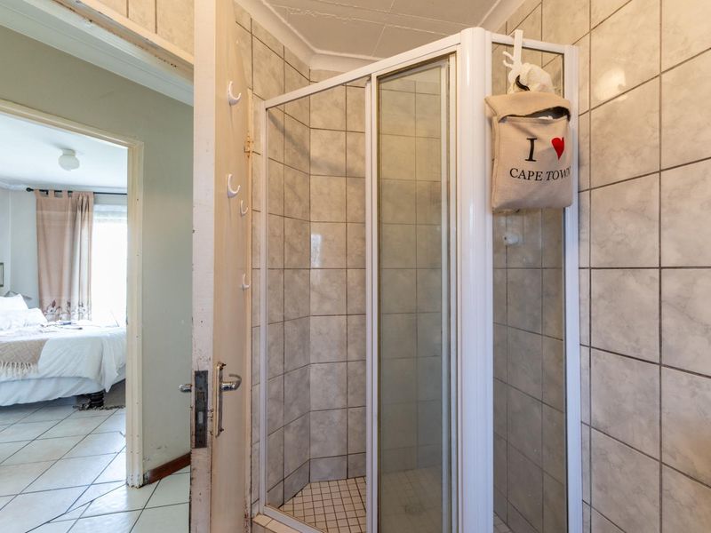 A functional bathroom featuring a corner shower enclosure with tiled walls and flooring, providing direct access to the adjacent bedroom.