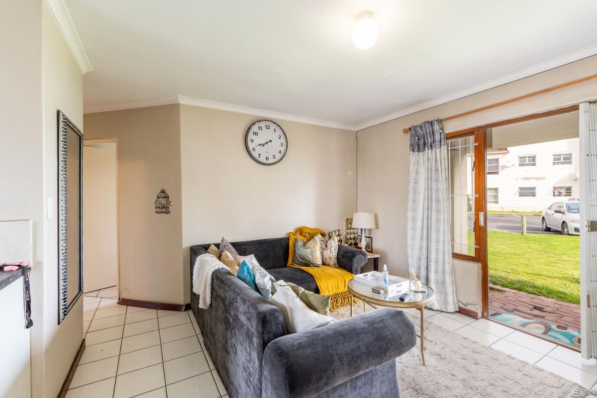 A living room featuring tiled flooring and a sliding glass door providing access to the exterior, with neutral wall finishes and coved ceilings.