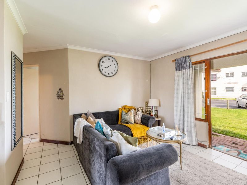 A living room featuring tiled flooring and a sliding glass door providing access to the exterior, with neutral wall finishes and coved ceilings.
