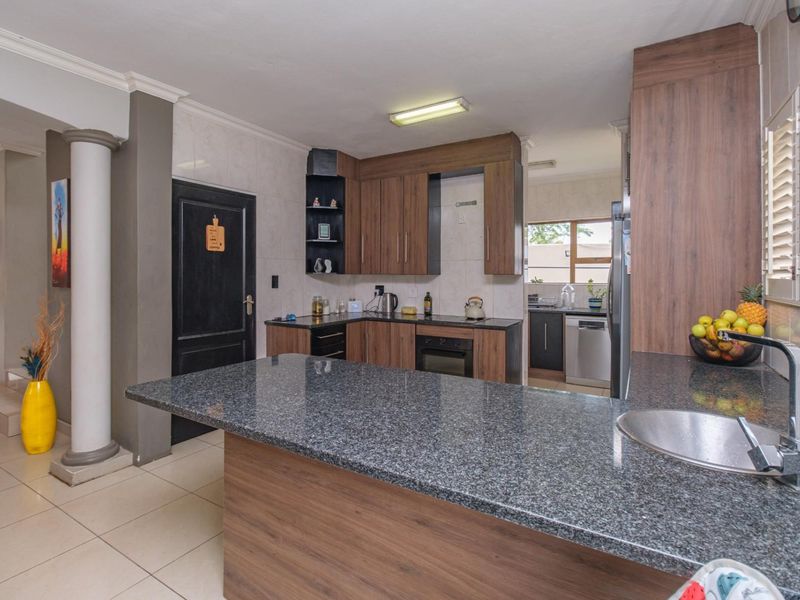 A functional kitchen featuring granite countertops, fitted wood-finish cabinetry, a built-in oven, and a breakfast bar area with an integrated sink.