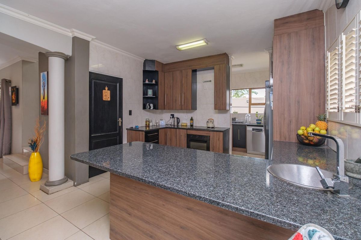 A functional kitchen featuring granite countertops, fitted wood-finish cabinetry, a built-in oven, and a breakfast bar area with an integrated sink.