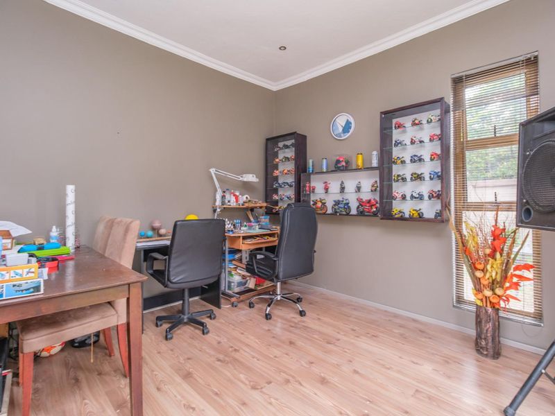 A bedroom featuring laminate flooring, crown molding, and venetian blinds, currently utilized as a hobby and workspace.
