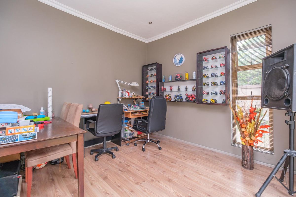 A bedroom featuring laminate flooring, crown molding, and venetian blinds, currently utilized as a hobby and workspace.