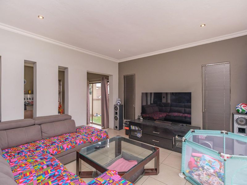 A spacious living room featuring tiled flooring, recessed downlighting, and a sliding glass door providing access to the outdoor area.