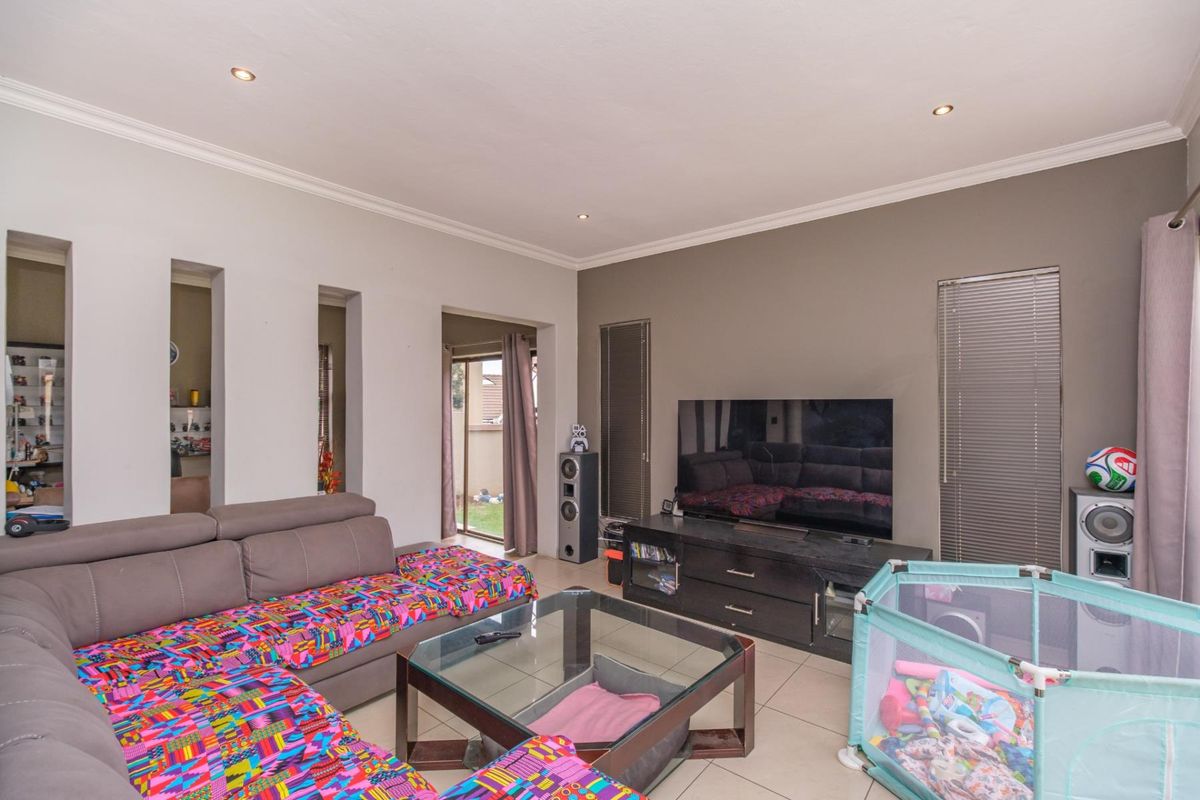 A spacious living room featuring tiled flooring, recessed downlighting, and a sliding glass door providing access to the outdoor area.