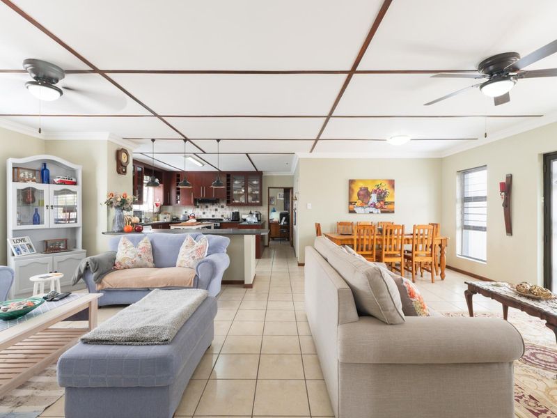 Spacious open-plan living and dining area featuring tiled floors, ceiling fans, and a functional kitchen with built-in cabinetry and a central island.