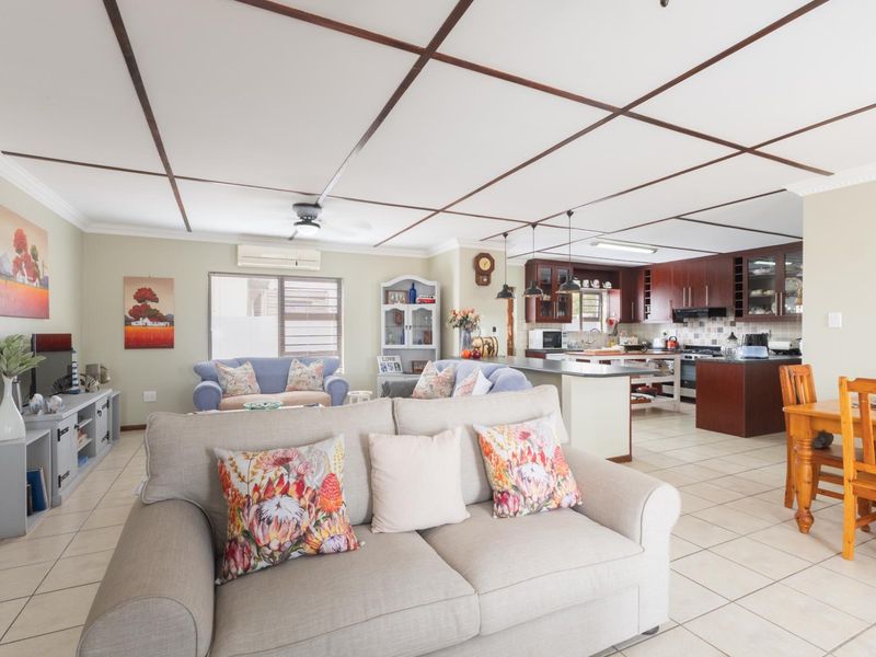 Spacious open-plan living, dining, and kitchen area featuring tiled floors, a central kitchen island, and a distinctive grid-patterned ceiling.